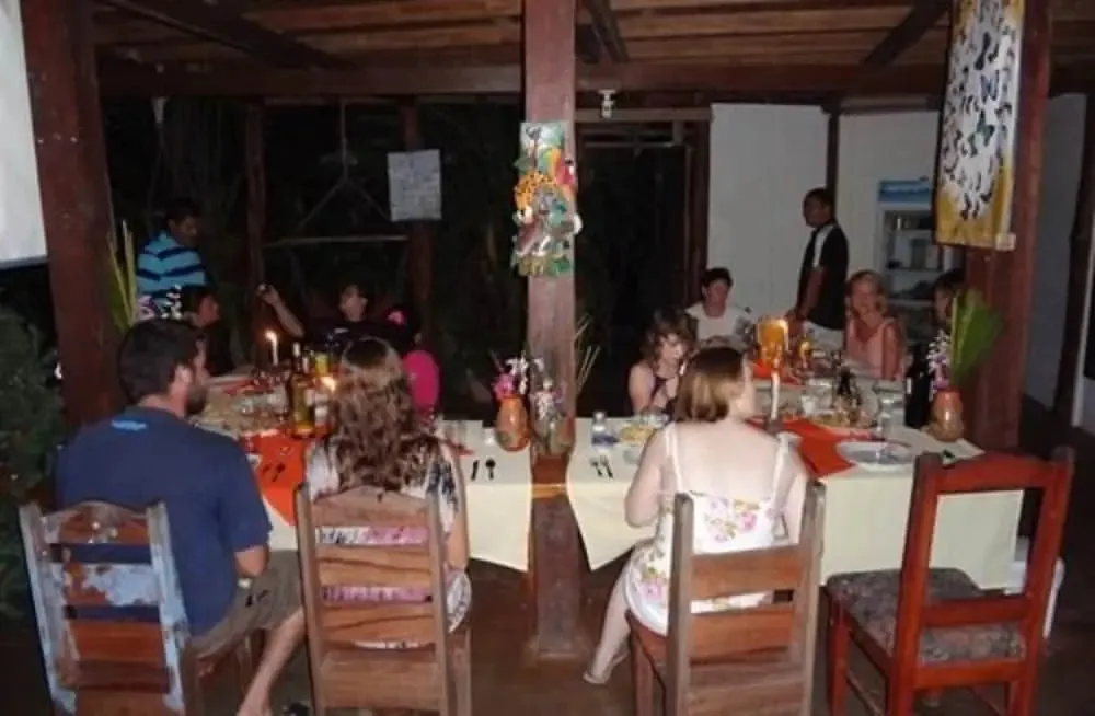 Des convives sont attablés dans une salle à manger éclairée à la bougie.