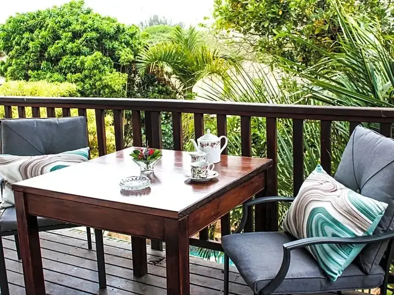 Une table et des fauteuils invitent à la détente sur une terrasse en bois.
