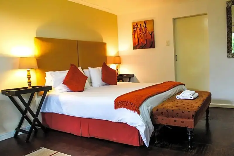 Une chambre lumineuse avec un grand lit recouvert d'une courtepointe et de coussins.