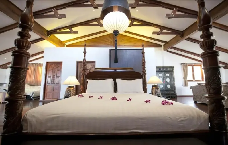 Une grande chambre à coucher avec un lit à baldaquin en bois sculpté.