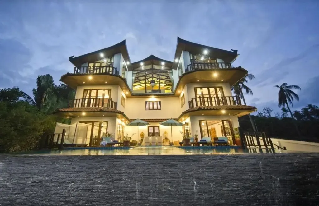 Bâtiment à plusieurs niveaux avec piscine et végétation luxuriante.