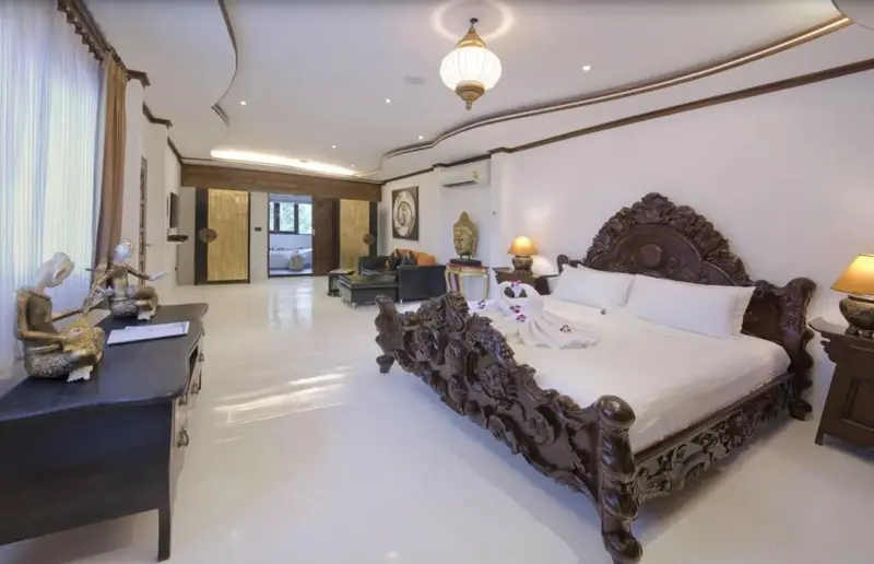 Une chambre spacieuse et lumineuse avec un grand lit sculpté.
