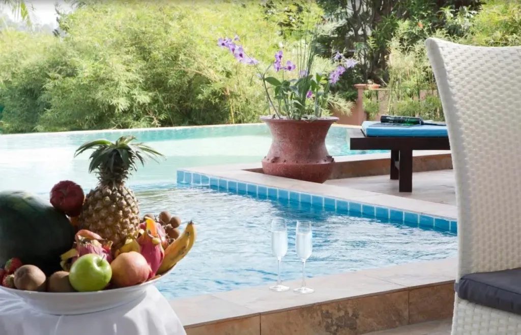 Une nature morte de fruits frais est présentée au bord d'une piscine turquoise.