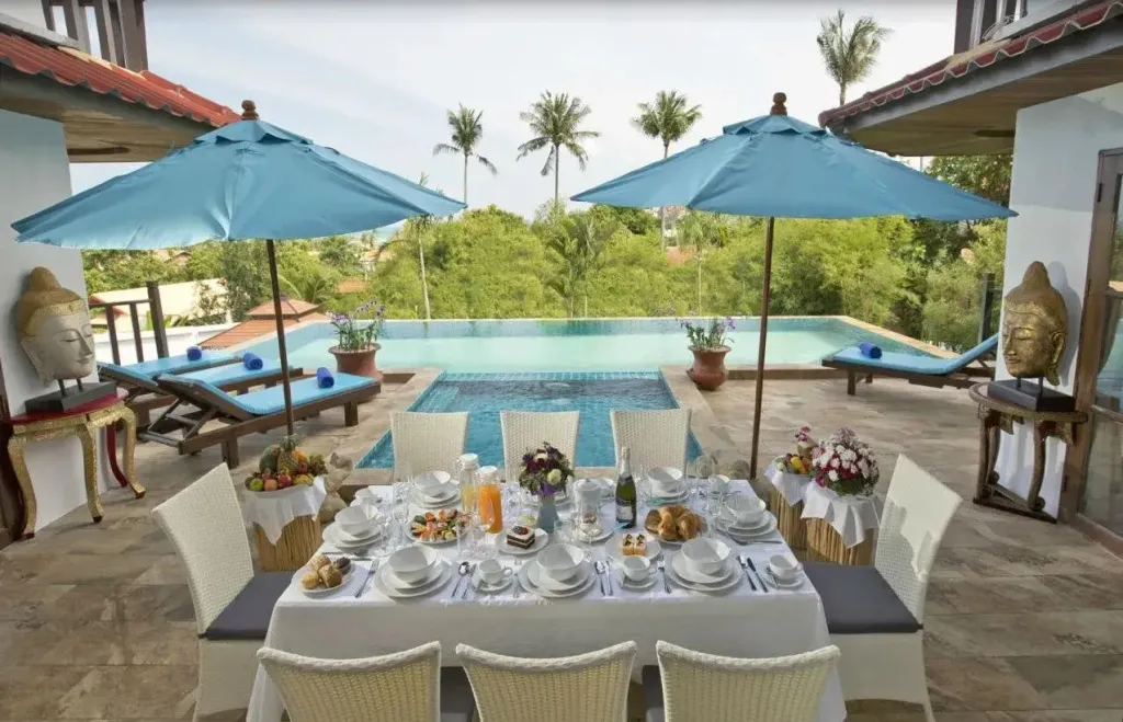 Une table dressée pour un repas en extérieur près d'une piscine.