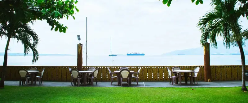 Terrasse avec tables et chaises donnant sur la mer.