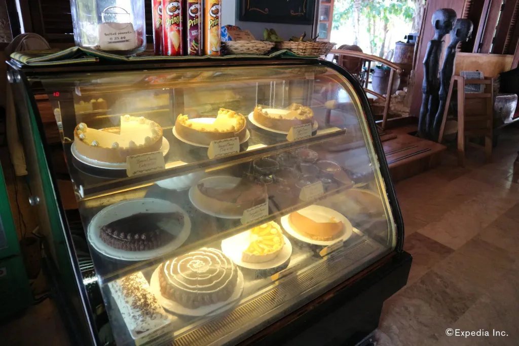 Une vitrine réfrigérée expose une variété de gâteaux et de tartes.