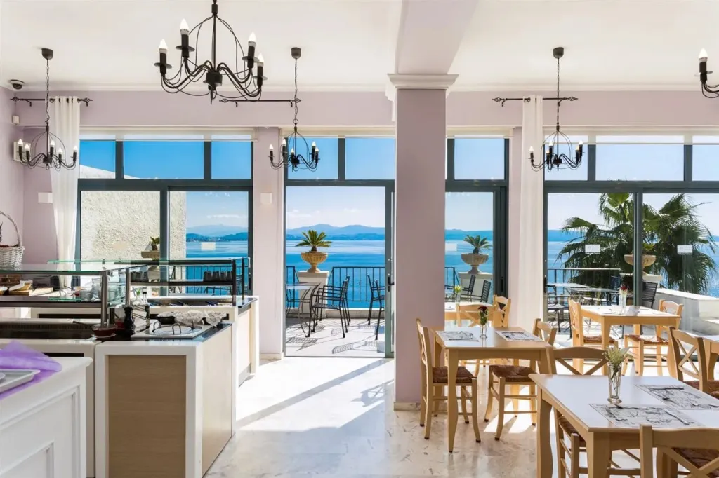Une salle lumineuse avec un comptoir de service et des tables donnant sur la mer.