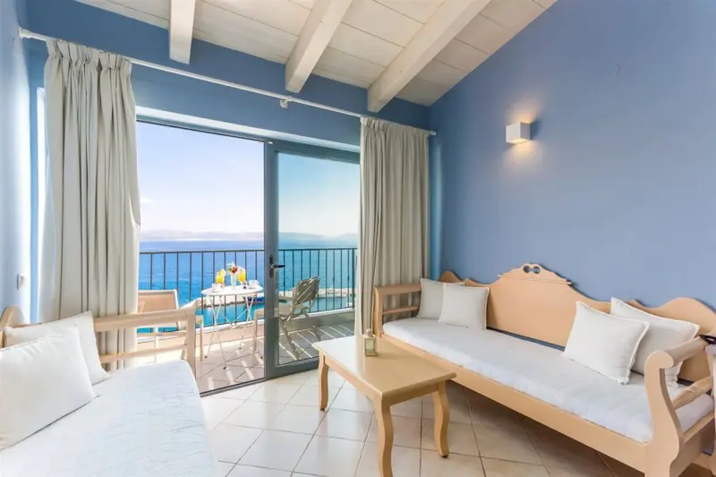 Espace de vie lumineux avec canapés et vue sur la mer depuis un balcon.