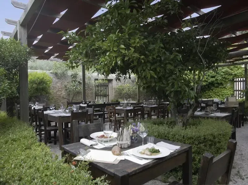 Une terrasse ombragée abrite des tables de restaurant dressées pour le service.