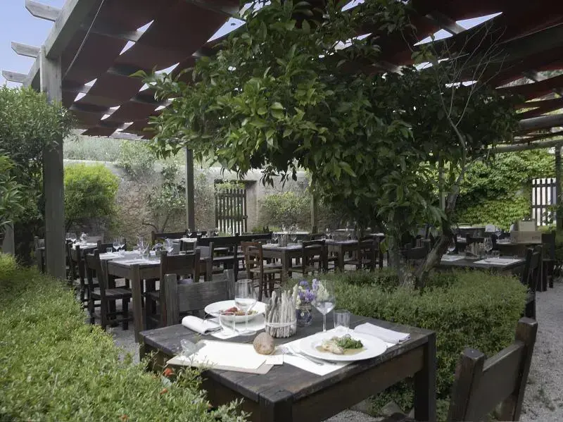 Une terrasse ombragée abrite des tables de restaurant dressées pour le service.