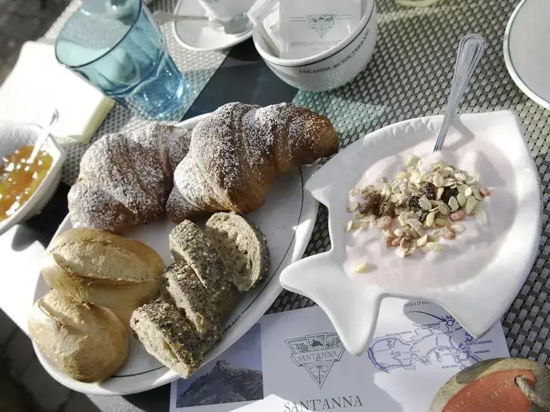 Une table est dressée avec des viennoiseries, des confitures et une préparation crémeuse.