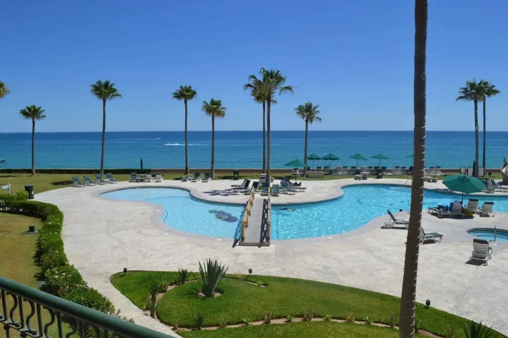 Piscine en forme d'île avec transats et palmiers en bord de mer.