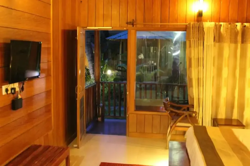 Une chambre lumineuse s'ouvre sur une terrasse en bois.