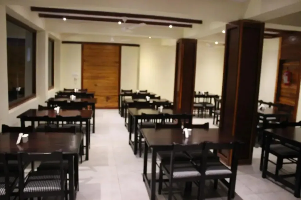 Une salle lumineuse est aménagée avec des tables et des chaises.