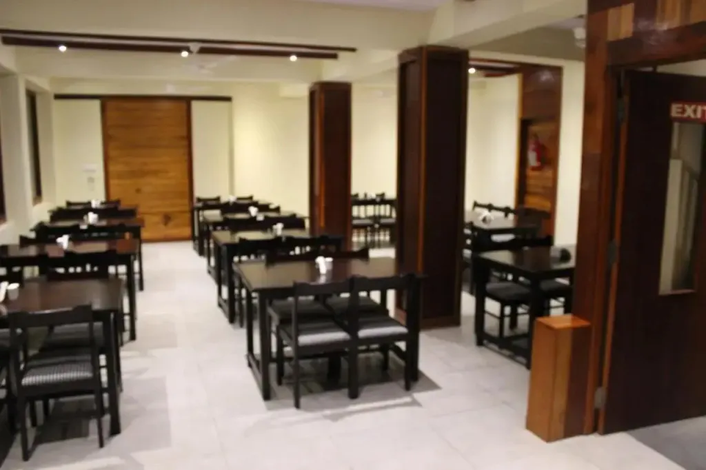 Une salle lumineuse avec des tables et des chaises disposées pour les repas.