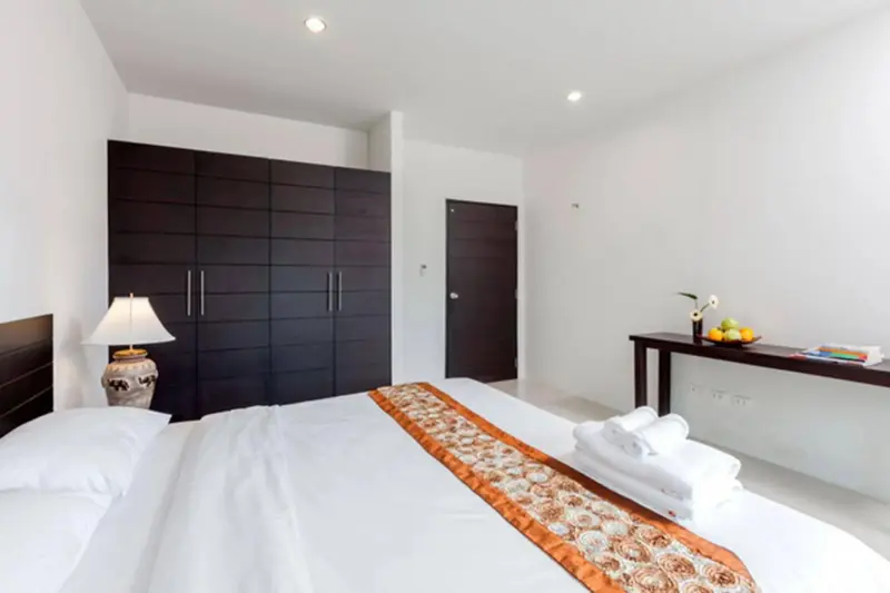 Une chambre lumineuse avec un grand lit et un meuble de rangement sombre.