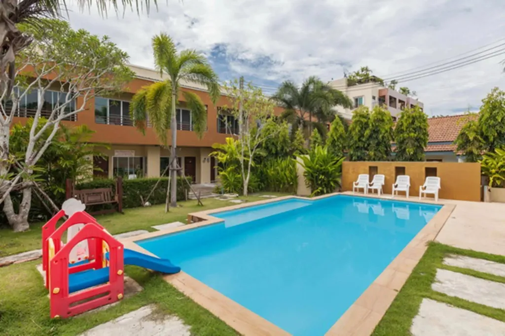 Une piscine rectangulaire bordée d'une pelouse verdoyante et de quelques transats.