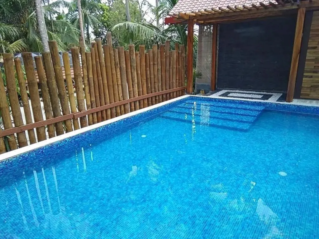 Piscine rectangulaire bleue avec escalier et bordure en mosaïque.