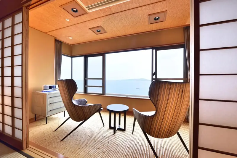 Espace de détente avec deux fauteuils face à une grande fenêtre donnant sur la mer.