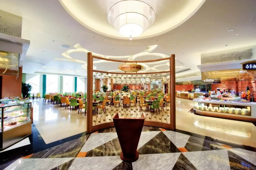 Une salle lumineuse avec des tables dressées et un buffet garni.