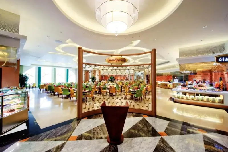 Une salle lumineuse avec des tables dressées et un buffet garni.