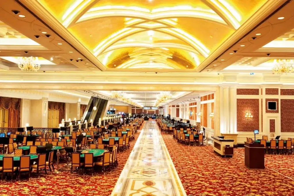Une vaste salle lumineuse est aménagée en espace de jeux avec de nombreuses tables et chaises.