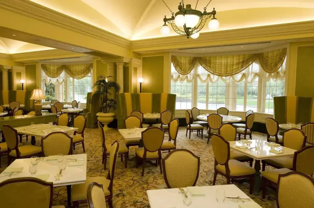 Une salle lumineuse avec des tables dressées pour un repas.
