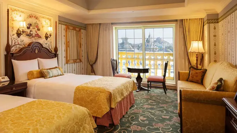 Chambre lumineuse avec lits et espace détente donnant sur une vue extérieure.