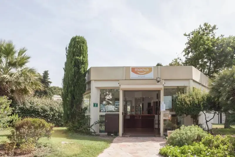 Façade d'un bâtiment avec une entrée vitrée et un jardin soigné.