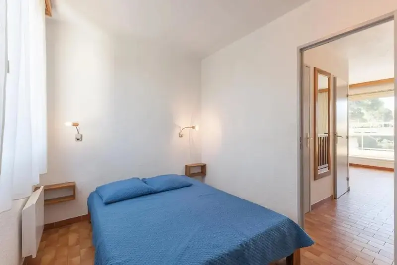 Une chambre lumineuse avec un lit simple donnant sur une terrasse.