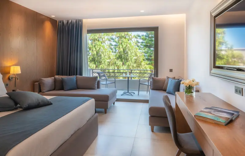 Une chambre lumineuse avec un lit et un espace salon donnant sur une terrasse.