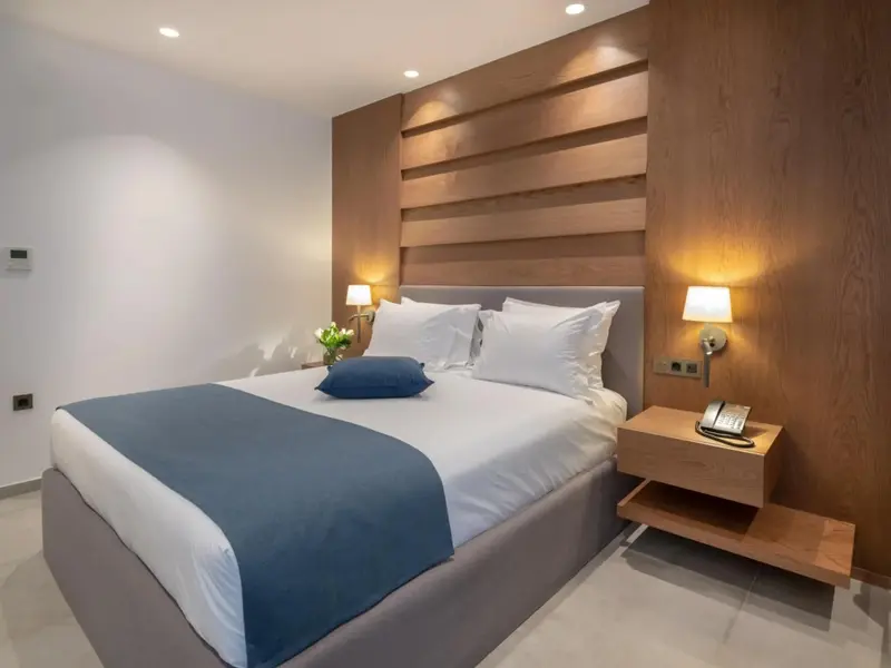 Une chambre lumineuse avec un grand lit recouvert d'une courtepointe bleue et de coussins blancs.