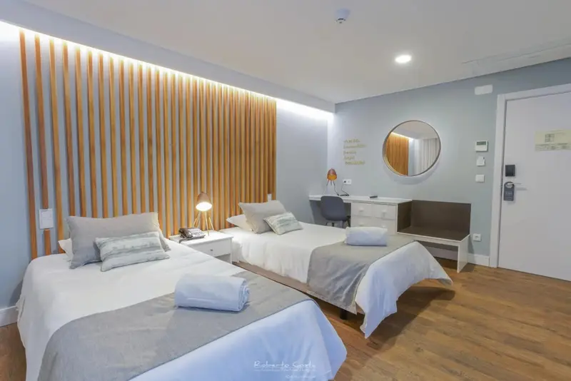 Chambre lumineuse avec deux lits simples et un décor mural en bois.