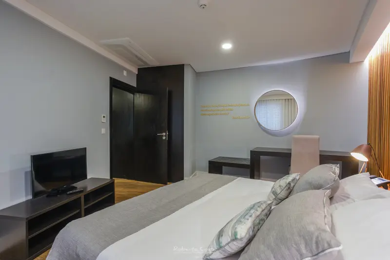 Une chambre lumineuse avec un grand lit et un téléviseur.