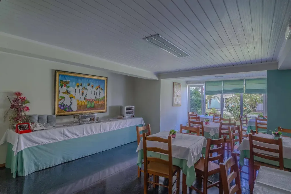 Une salle lumineuse avec des tables dressées pour un repas.