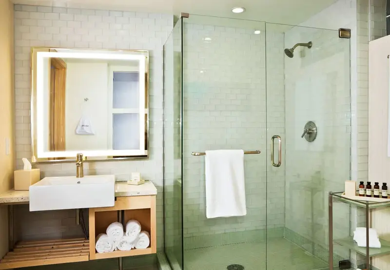 Une salle de bain lumineuse avec douche à l'italienne et vasque sur meuble.