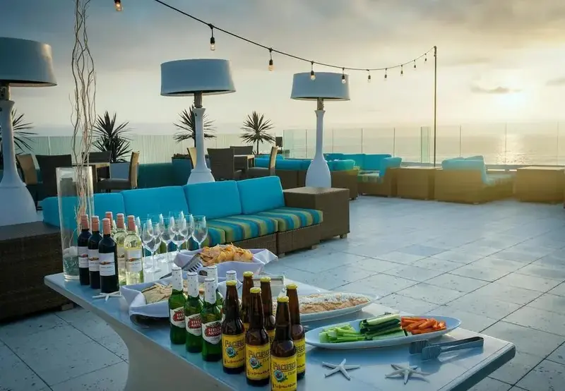 Une terrasse aménagée avec des canapés et une table garnie de boissons et de collations.