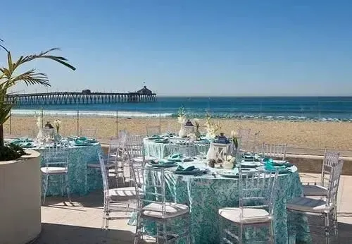 Tables dressées en extérieur avec vue sur la plage et une jetée.
