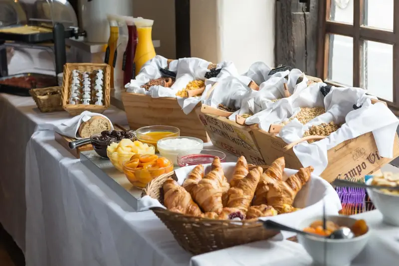 Un buffet propose des viennoiseries, des fruits et des céréales.