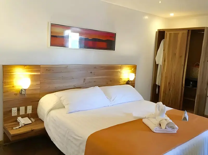 Une chambre lumineuse avec un grand lit recouvert d'une courtepointe orange et de coussins blancs.