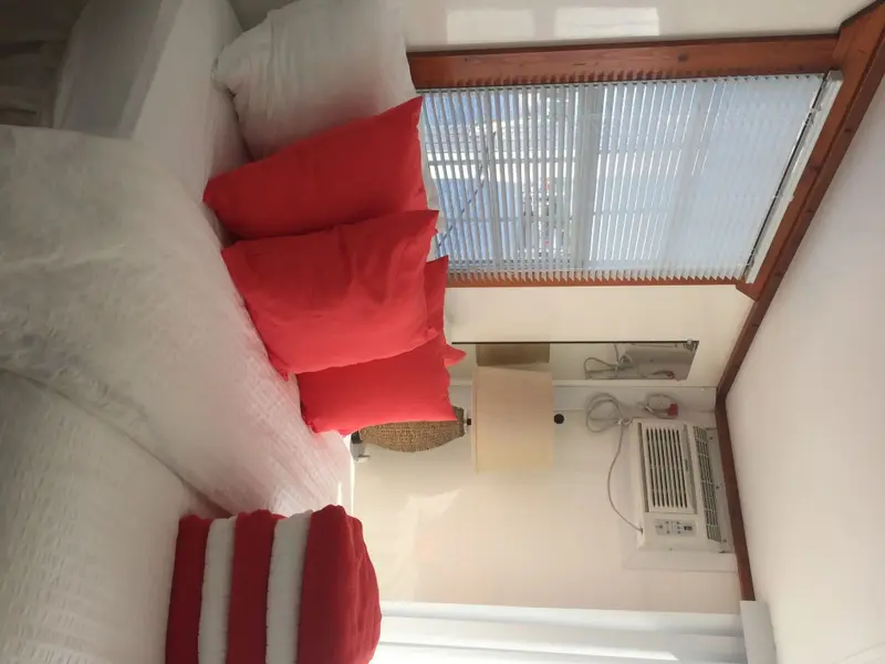 Lits blancs et oreillers rouges dans une chambre lumineuse.