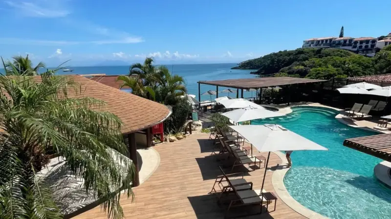 Terrasse en bois avec transats et piscine au bord de la mer.