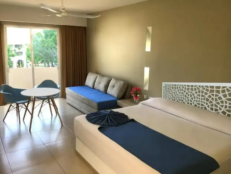 Une chambre lumineuse avec un lit double et un coin salon.