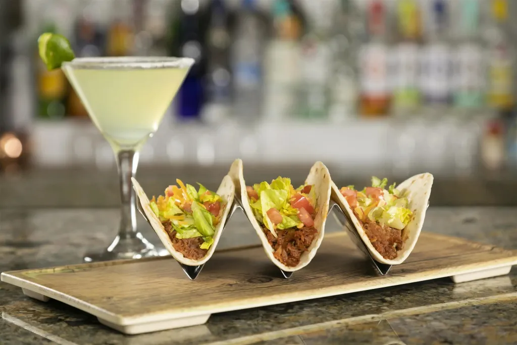 Présentation de tacos et d'un cocktail sur un comptoir.