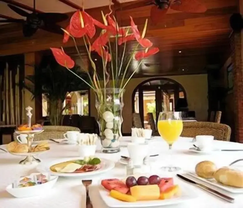 Une table est dressée pour le petit-déjeuner avec des viennoiseries, des fruits et des boissons.