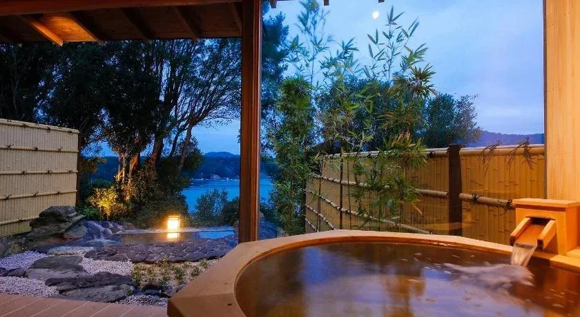 Baignoire en bois avec vue sur un paysage côtier au crépuscule.
