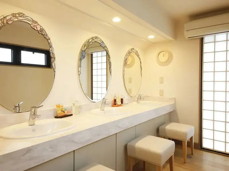Trois vasques sur un long meuble dans une salle de bain lumineuse.