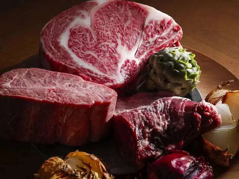 Présentation de morceaux de viande rouge et d'artichauts sur une surface en bois.