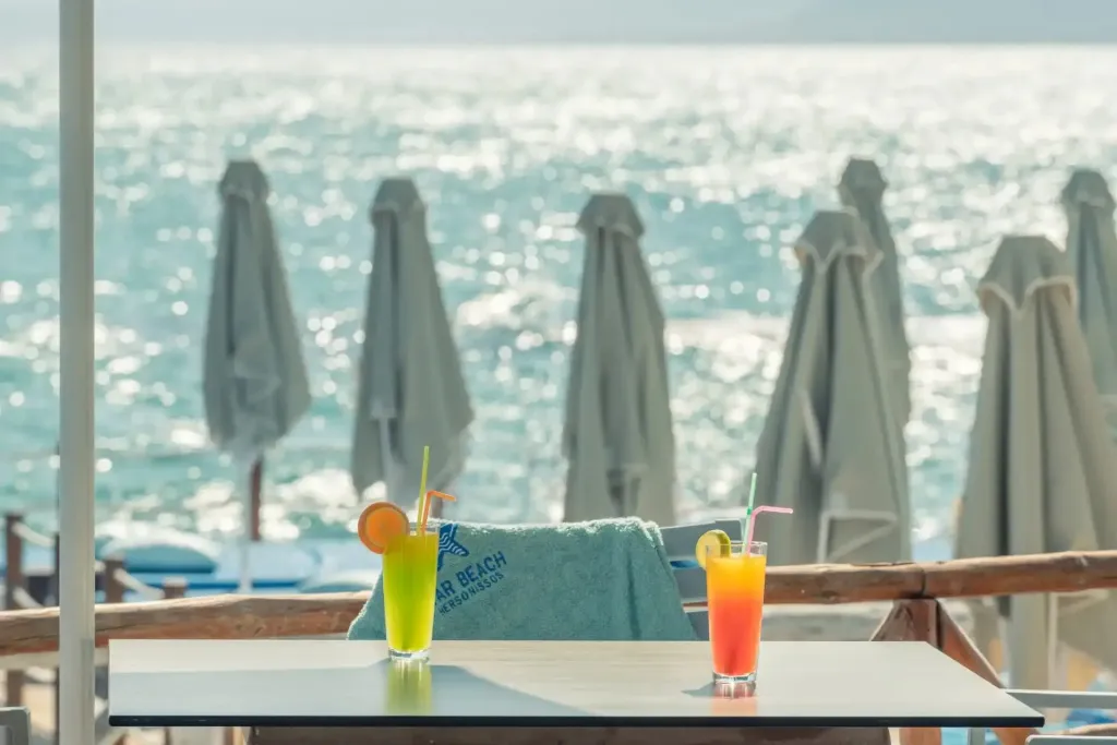 Deux cocktails colorés sont servis sur une table en terrasse avec vue sur la mer.