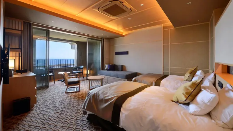 Une chambre spacieuse avec lits et espace salon donnant sur une vue mer.